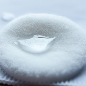 A close-up of a cotton pad with a few drops of liquid on it.