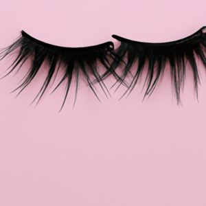 A pair of black eyelashes against a bright pink background.