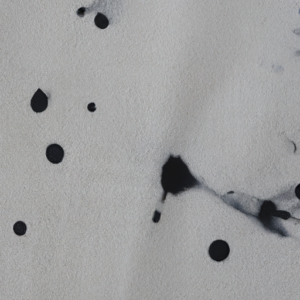 Close-up of a white fabric with small black smudges.