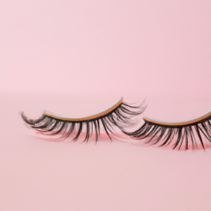 An up-close view of a pair of fake eyelashes with a pink background.