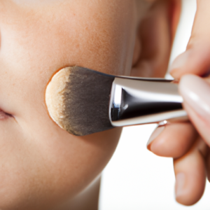 A close-up of a makeup brush applying foundation to a woman's cheek.