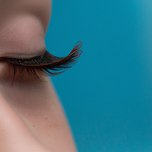 Close-up of long, lush eyelashes against a light blue background.