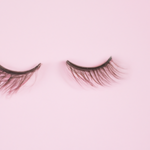 A pair of long, luxurious mink eyelashes against a light pink background.