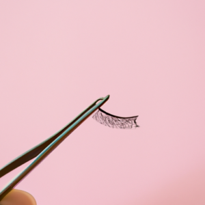 A pair of tweezers holding a single eyelash against a pink background.