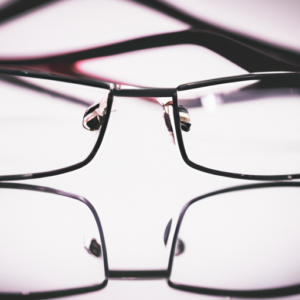 A pair of glasses with one lens reflecting a business suit.