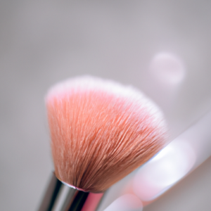 A close-up of a makeup brush with a soft pink blush hue.