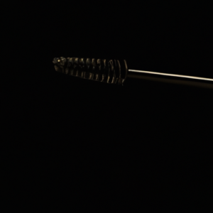 A close-up of a mascara wand against a black background.